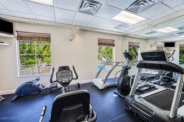 exercise room featuring baseboards, a paneled ceiling, and visible vents