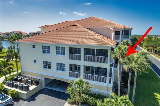 rear view of property featuring central AC unit, a tiled roof, and a sunroom