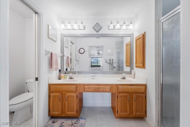 bathroom featuring double vanity, a sink, a stall shower, and toilet