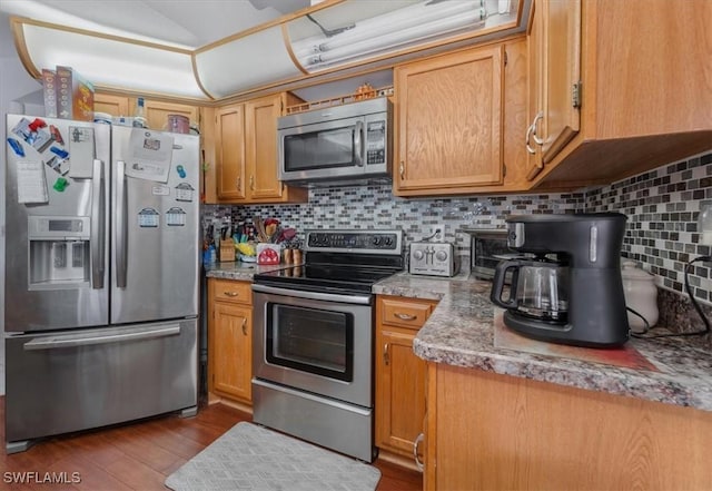 kitchen featuring backsplash, appliances with stainless steel finishes, wood finished floors, and light countertops