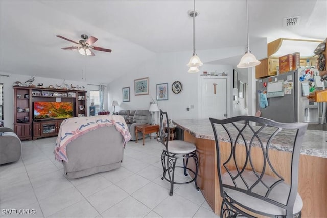living room with vaulted ceiling, light tile patterned floors, a ceiling fan, and visible vents
