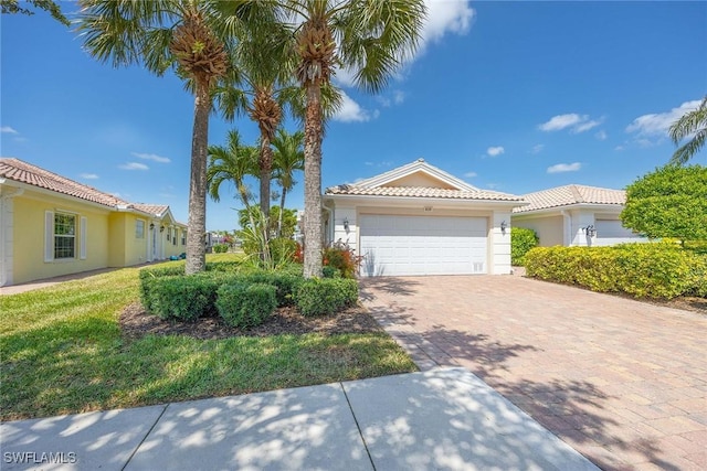 ranch-style home featuring an attached garage, driveway, a tile roof, and stucco siding