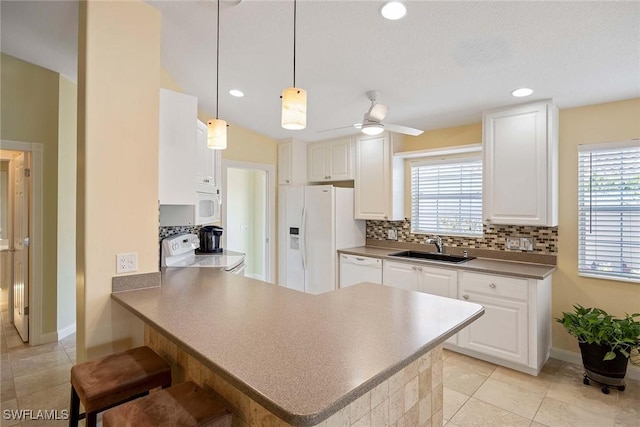 kitchen with decorative backsplash, a sink, a peninsula, white appliances, and white cabinetry