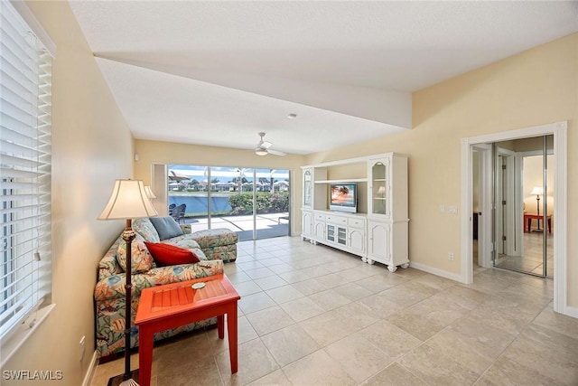 living area featuring baseboards and a ceiling fan