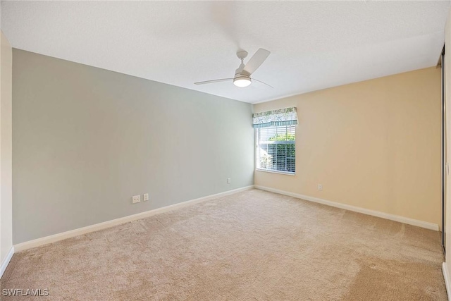 carpeted empty room featuring baseboards and ceiling fan