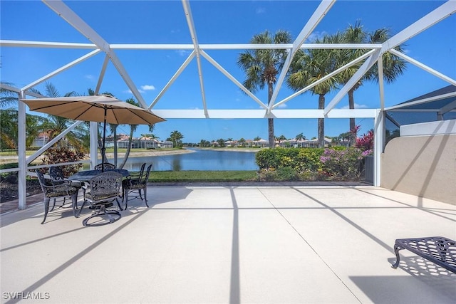 view of patio featuring outdoor dining area, glass enclosure, and a water view