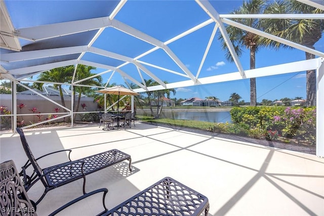 view of patio with a water view, a lanai, and outdoor dining space