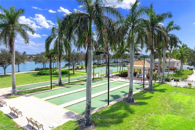 view of property's community with a lawn, fence, and a water view