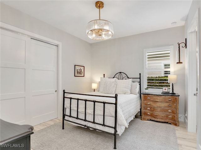 14243 Galley Ct, Naples, FL 34114 - bedroom with a closet, light wood-type flooring, and a chandelier