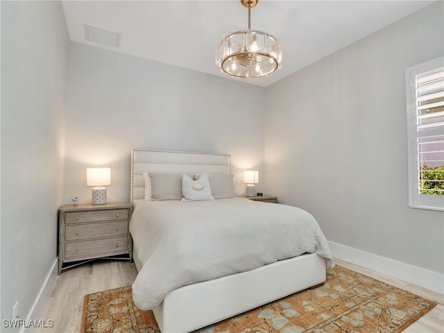 14243 Galley Ct, Naples, FL 34114 - bedroom featuring visible vents, baseboards, wood finished floors, and a notable chandelier