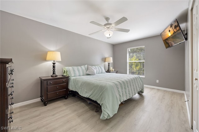 bedroom with light wood-style flooring, baseboards, and a ceiling fan