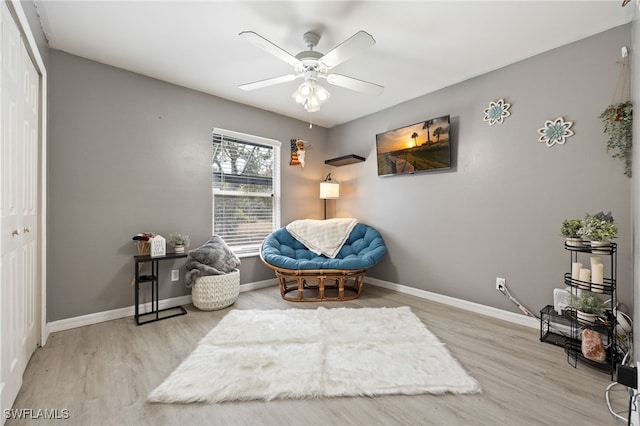 living area featuring wood finished floors, ceiling fan, and baseboards