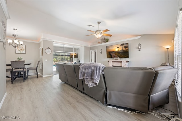 living area featuring light wood-type flooring, a chandelier, a ceiling fan, vaulted ceiling, and baseboards