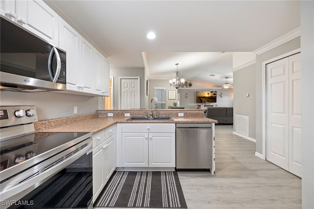 kitchen featuring appliances with stainless steel finishes, a sink, a peninsula, white cabinetry, and ornamental molding