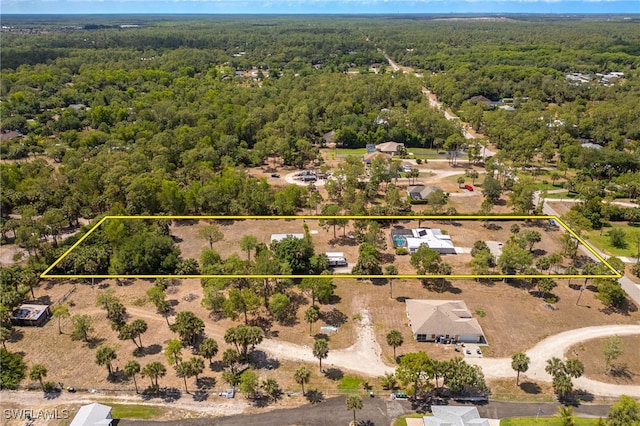 aerial view of property and surrounding area with a heavily wooded area and property parcel outlined