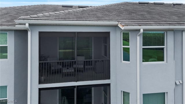 view of side of property with a tile roof and stucco siding