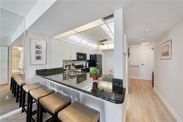 260 Seaview Ct Unit 402, Marco Island, FL 34145 - kitchen featuring visible vents, a peninsula, light wood-type flooring, a sink, and black appliances