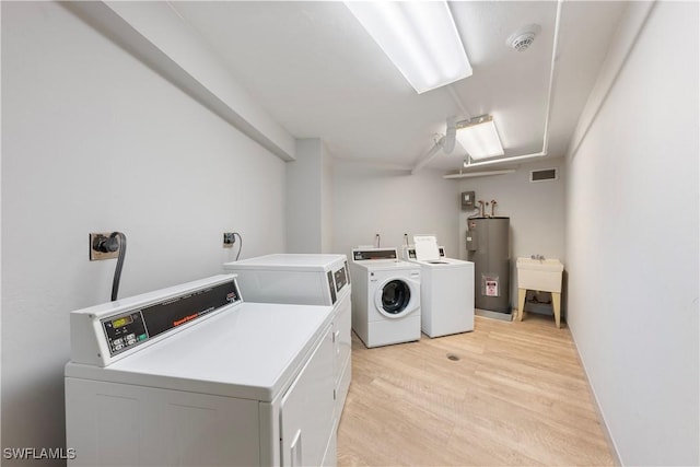 260 Seaview Ct Unit 402, Marco Island, FL 34145 - clothes washing area featuring visible vents, a sink, water heater, light wood-style flooring, and washer and clothes dryer