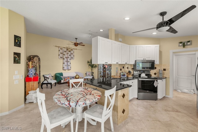 4748 San Carlo Ct, Naples, FL 34109 - kitchen with a peninsula, a ceiling fan, dark countertops, stainless steel appliances, and white cabinets