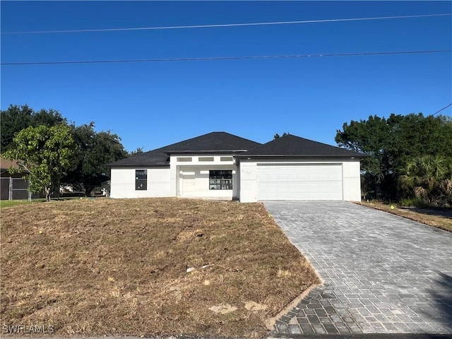 view of front of home featuring a garage, decorative driveway, a front lawn, and stucco siding