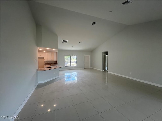 unfurnished living room featuring visible vents, baseboards, light tile patterned floors, and high vaulted ceiling