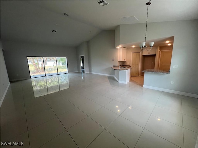 unfurnished living room with light tile patterned flooring, high vaulted ceiling, a chandelier, baseboards, and visible vents