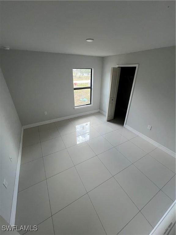 empty room with baseboards, recessed lighting, and light tile patterned floors