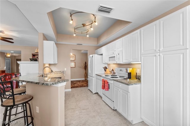 11016 Mill Creek Way Unit 2403, Fort Myers, FL 33913 - kitchen featuring white appliances, a kitchen bar, a raised ceiling, baseboards, and white cabinets