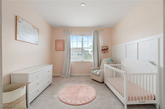 bedroom with a nursery area and light carpet