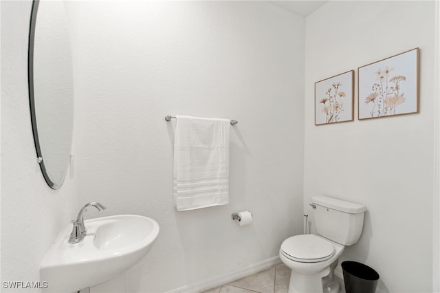 bathroom featuring toilet, tile patterned flooring, a sink, and baseboards