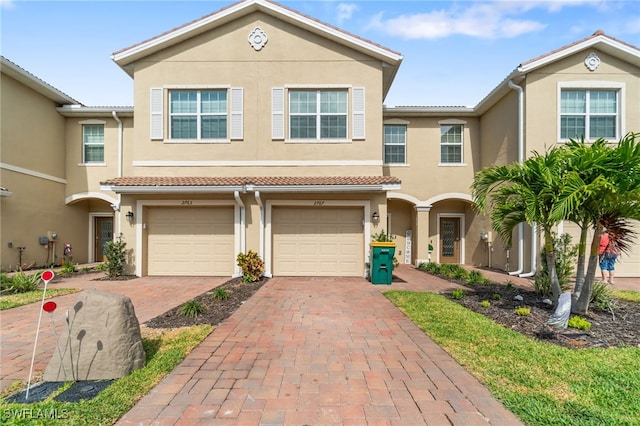 view of property with driveway, stucco siding, and an attached garage