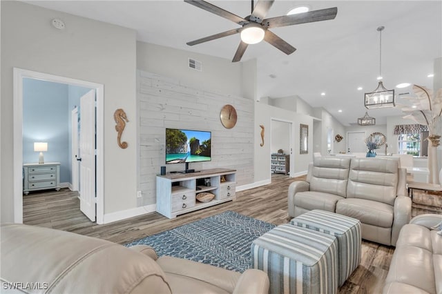living room featuring ceiling fan with notable chandelier, wood finished floors, and visible vents