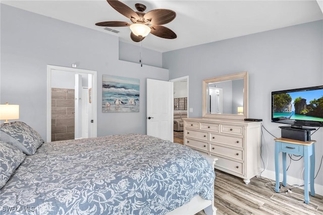 bedroom with light wood finished floors, a ceiling fan, baseboards, ensuite bathroom, and visible vents
