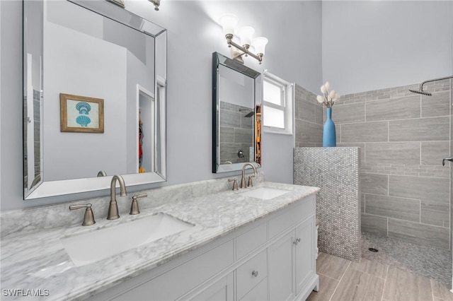 full bath with double vanity, a sink, and tiled shower