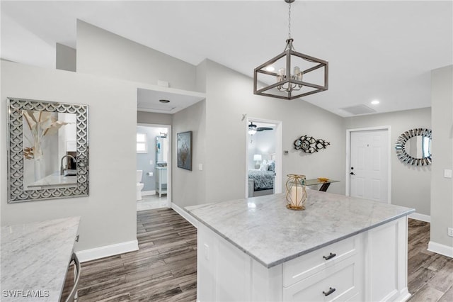 kitchen with dark wood finished floors, baseboards, white cabinets, a notable chandelier, and lofted ceiling