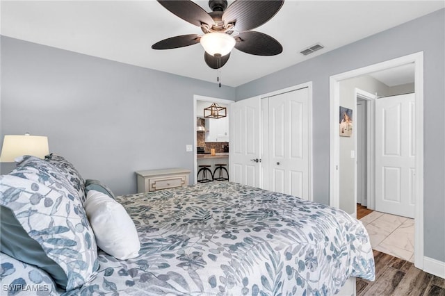 bedroom featuring a ceiling fan, visible vents, wood finished floors, and a closet