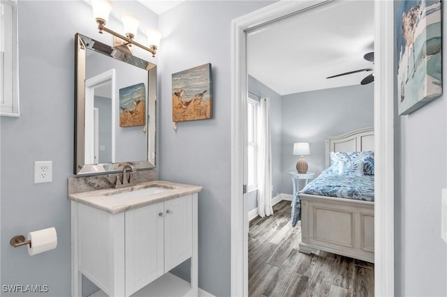 bathroom featuring baseboards, ceiling fan, wood finished floors, and vanity