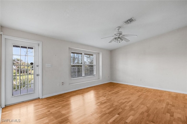 empty room with plenty of natural light, a ceiling fan, and light wood finished floors