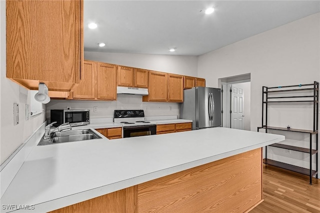 kitchen featuring stainless steel appliances, under cabinet range hood, a sink, vaulted ceiling, and light countertops