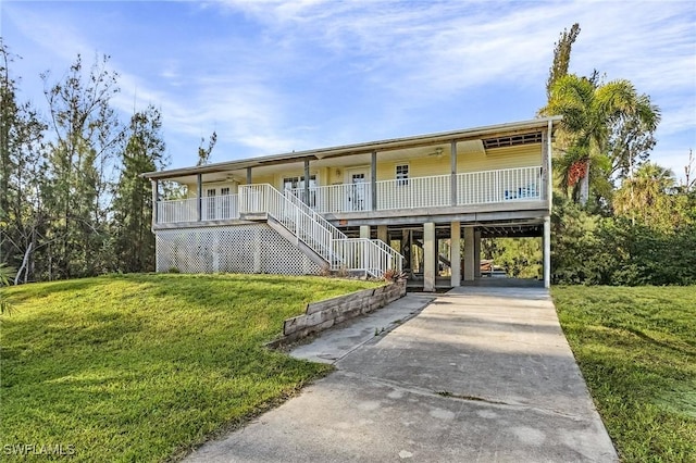 view of front of property featuring a front yard, a carport, concrete driveway, a porch, and stairs