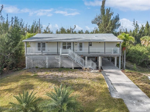 view of front of property with a carport, a front lawn, concrete driveway, a porch, and stairs