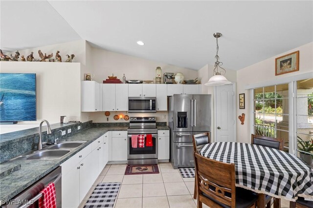 kitchen featuring a sink, vaulted ceiling, dark countertops, stainless steel appliances, and white cabinets