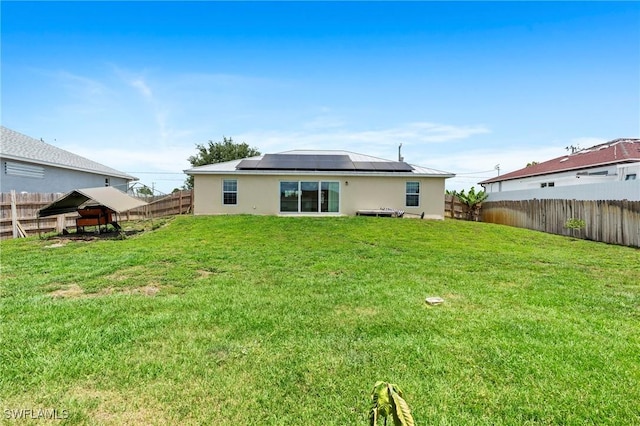 3303 32nd St SW, Lehigh Acres, FL 33976 - back of house featuring solar panels, a fenced backyard, and stucco siding