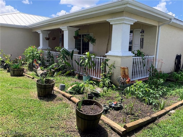 3303 32nd St SW, Lehigh Acres, FL 33976 - view of side of home featuring a porch, a standing seam roof, stucco siding, and a yard
