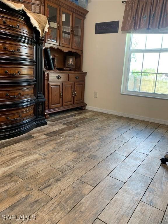 3303 32nd St SW, Lehigh Acres, FL 33976 - unfurnished living room featuring hardwood / wood-style flooring and baseboards
