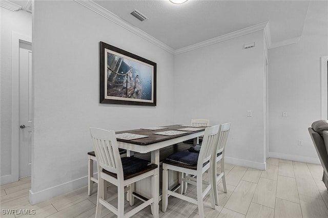 dining space featuring crown molding, baseboards, and visible vents
