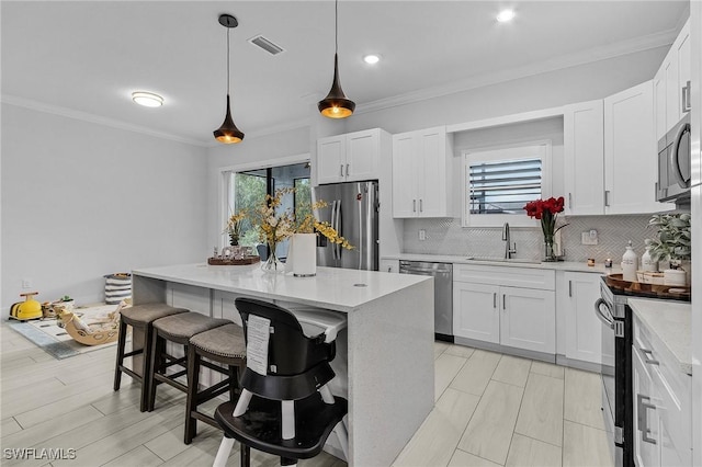 kitchen featuring visible vents, decorative backsplash, a breakfast bar area, a sink, and appliances with stainless steel finishes