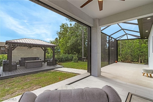 view of patio / terrace with a gazebo, a deck, an outdoor living space, a ceiling fan, and a lanai