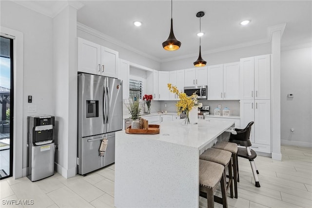 kitchen with a kitchen breakfast bar, a center island, white cabinetry, appliances with stainless steel finishes, and hanging light fixtures