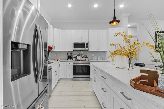 kitchen with white cabinets, appliances with stainless steel finishes, decorative light fixtures, decorative backsplash, and ornamental molding